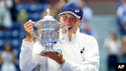 Iga Swiatek of Poland poses for a photo with the championship trophy after defeating Ons Jabeur of Tunisia in the women's singles final of the US Open tennis championships, Sept. 10, 2022, in New York.