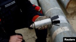 FILE - A Ukrainian military serviceman holds a defused cluster bomb 