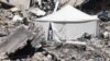 A displaced Palestinian stands at the entrance of a tent set up amid the rubble of a building damaged during Israeli bombardment in Rafah, on the southern Gaza Strip.