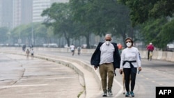 People walk along the shoreline of Lake Michigan with heavy smoke from the Canadian wildfires in the background, on June 27, 2023, in Chicago.