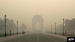 Pedestrians walk along the Kartavya Path in front of the India Gate amid heavy smoggy conditions in New Delhi on November 13, 2023.