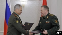 Russian Defense Minister Sergei Shoigu and his Belarusian counterpart Viktor Khrenin shake hands after signing a deal on the deployment of some of Russia's tactical nuclear weapons in Belarus, in Minsk, May 25, 2023. (Russian Defense Ministry via AFP)