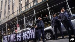 Demonstrators unveil a banner outside Manhattan's district attorney office, supporting a grand jury vote to indict former President Donald Trump, March 30, 2023, in New York. 