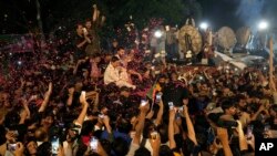 Supporters throw rose petals toward a vehicle carrying Pakistan's former Prime Minister Imran Khan to greet him upon his arrival at his home in Lahore, Pakistan, May 13, 2023. 