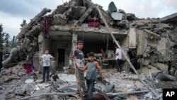 FILE - Palestinians look at the destruction after an Israeli airstrike in Deir al Balah, Gaza Strip, April 30, 2024.