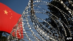 The border wall between China and Myanmar with barbed wire and a Chinese national flag