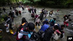 FILE - Migrants, mostly Venezuelans, cross a river during their journey through the Darien Gap from Colombia into Panama, hoping to reach the US, Oct. 15, 2022. 