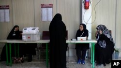 Staff members of a polling station attend to their stations during the parliamentary runoff elections in Tehran, Iran, May 10, 2024. I