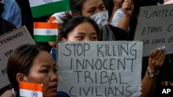 Members of the Kuki tribe, protesting the killing of tribals in their northeastern home state of Manipur, hold Indian flags and placards during a sit-in in New Delhi, India, May 29, 2023.