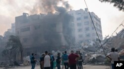 FILE - Journalists observe as Palestinians inspect the rubble of a building after it was struck by an Israeli airstrike, in Gaza City, Oct. 8, 2023.