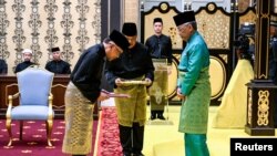 Malaysia's King Sultan Abdullah Sultan Ahmad Shah (R) and Malaysia's newly appointed Prime Minister Anwar Ibrahim (L) take part in the swearing-in ceremony at the National Palace in Kuala Lumpur, Nov. 24, 2022.