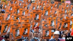 FILE - In this file photo taken on February 28, 2021 protesters hold posters with the image of detained civilian leader Aung San Suu Kyi during a demonstration against the military coup in Naypyidaw, Myanmar.