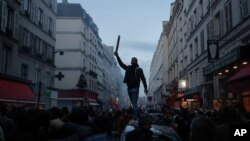 A members of Kurdish community stands on the top of a car during clashes with police officers near the crime scene where a shooting took place in Paris, Dec. 23, 2022.