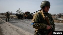 A Ukrainian serviceman stands near the wreck of a Russian tank on the front line in the Kyiv region, Ukraine, March 28, 2022. 