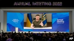 Ukrainian President Volodymyr Zelenskyy displayed on a screen as he addresses the audience from Kyiv on a screen during the World Economic Forum in Davos, Switzerland, May 23, 2022.