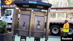 A worker removes the last public payphone near Times Square in New York City, May 23, 2022. 