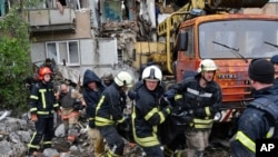 Rescuers carry the body of a civilian at a site of an apartment building destroyed by Russian shelling in Bakhmut, Donetsk region, Ukraine, May 18, 2022.