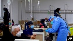 In this photo released by Xinhua News Agency, a medical worker helps a patient at a community health care institution in Shanghai, China, Jan. 5, 2023. 