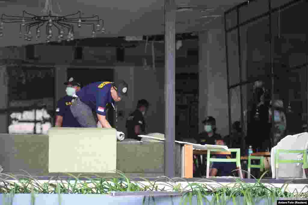 Indonesian policemen examine debris from a bomb blast inside a Starbucks coffee at Thamrin business district in Jakarta.