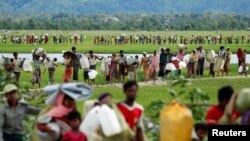 Rohingya refugees walk through rice fields after crossing the border from Myanmar into Palang Khali, Bangladesh, October 19, 2017. © 2017 Jorge Silva/Reuters