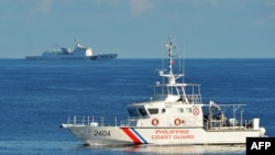 This file photo taken on May 14, 2019 shows a Philippines' coast guard ship (R) sailing past a Chinese coast guard ship during a joint search and rescue exercise between the Philippines and US coast guards near Scarborough Shoal in the South China Sea.