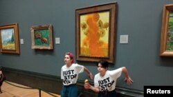 Activists of "Just Stop Oil" glue their hands to the wall after throwing soup at a van Gogh's "Sunflowers" painting at the National Gallery in London, Britain, Oct. 14, 2022. (Just Stop Oil/Handout via Reuters)