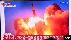 People watch a television news broadcast showing file footage of a North Korean missile test, at a railway station in Seoul on September 28, 2021, after North Korea fired an "unidentified projectile" into the sea off its east coast, according to the South