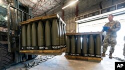 U.S. Air Force Staff Sgt. Cody Brown, right, with the 436th Aerial Port Squadron, checks pallets of 155 mm shells ultimately bound for Ukraine.