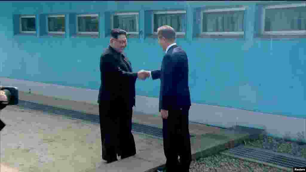 North Korean leader Kim Jong Un shakes hands with South Korean President Moon Jae-in at the concrete border as both of them arrive for the inter-Korean summit at the truce village of Panmunjom, in this still frame taken from video, South Korea April 27, 2