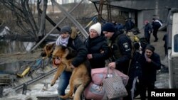 A man carries a dog as people flee, amid Russia's invasion of Ukraine, in Romanivka, Ukraine, March 9, 2022. 