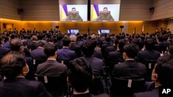 Members of Japan's lower house parliament applaud as Ukrainian President Volodymyr Zelenskyy delivering a virtual address to Japanese lawmakers in Tokyo, March 23, 2022.