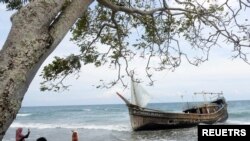 A wooden boat is used to carry RohingyaÊrefugees rest at a beach in Ladong village Indonesia, December 25, 2022.