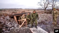 FILE - Russian Defense Minister Sergei Shoigu, center, walks out of a trench, escorted by a group of officers as he inspects Russian troops at an undisclosed location in Ukraine, Dec. 22, 2022.. 