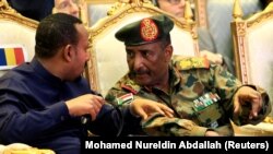 Sudan's Head of Transitional Military Council, Lieutenant General Abdel Fattah Al-Burhan, talks to Ethiopia's Prime Minister Abiy Ahmed during the signing of the power sharing deal, that paves the way for a transitional government, and eventual elections,