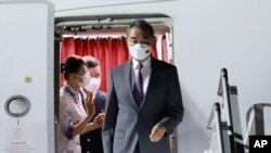 In this photo released by Agence Kampuchea Press (AKP), Chinese Foreign Minister Wang Yi, right, arrives at Phnom Penh International Airport in Phnom Penh, Cambodia, Tuesday, Aug. 2, 2022.