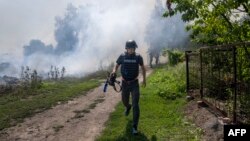 An AFP journalist runs as smoke rises behind after a bombardment in Bakhmut, Eastern Ukraine, July 31, 2022.