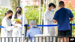 Health care workers with New York City Department of Health and Mental Hygiene help people register for the monkeypox vaccine at one of the city's vaccination sites, July 26, 2022, in New York.