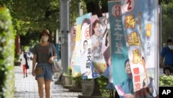 People walk past candidate's campaign flag in Taipei, Taiwan, Sunday, Nov. 20, 2022. Taiwan will hold local elections on November 26. (AP Photo/Chiang Ying-ying)