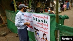 People chat with a barricade between them blocking off their street to prevent the spread of the coronavirus disease (COVID-19) in Yangon, Myanmar, September 12, 2020. REUTERS/Shwe Paw Mya Tin