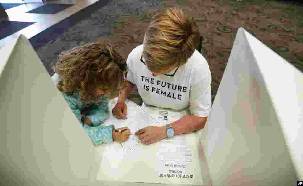 Kirsten Bosch, of Des Moines, Iowa, gets help from her six-year old daughter Parker, left, while voting in the general election in precinct 39 at the First Church of the Open Bible, Nov. 8, 2016, in Des Moines, Iowa. 