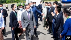 In this photo provided by Myanmar's Ministry of Information, Chinese Foreign Minister Wang Yi, center, is welcomed by Myanmar Foreign Ministry representatives and Chinese embassy officials upon his arrival at Nyaung Oo Airport in Bagan, Myanmar, July 2, 2