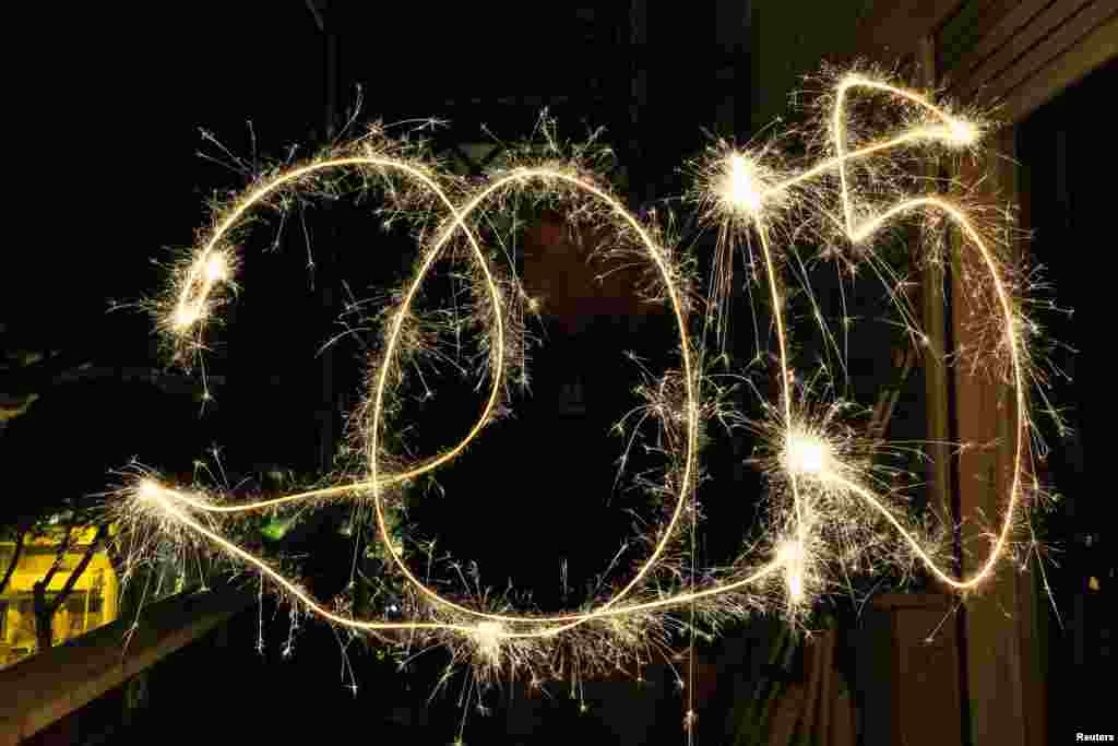 A man paints "2015" with the light of a sparkler as he celebrates the New Year in Rome, Jan. 1, 2015. 