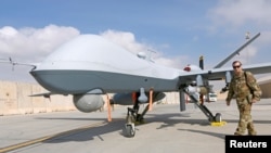 အမေရိကန် လေတပ်အရာရှိနဲ့ MQ-9 Reaper drone ကို အာဖဂန်စစ်အခြေစိုက်စခန်း ကန်ဒါဟာမှာ တွေ့ရစဉ်။