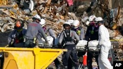 Search and rescue personnel remove remains on a stretcher as they work atop the rubble at the Champlain Towers South condo building, in Surfside, California, July 2, 2021.