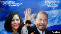 Yon sitwayen nikaragweyen ki t ap tcheke sèlfòn li devan yon banyè ki te fè reklam pou Prezidan Daniel Ortega ak Vis Prezidan Rosario Murillo pandan kanpay elektoral la nan Managwa, kapital Nikaragwa. (Foto: REUTERS/Maynor Valenzuela).