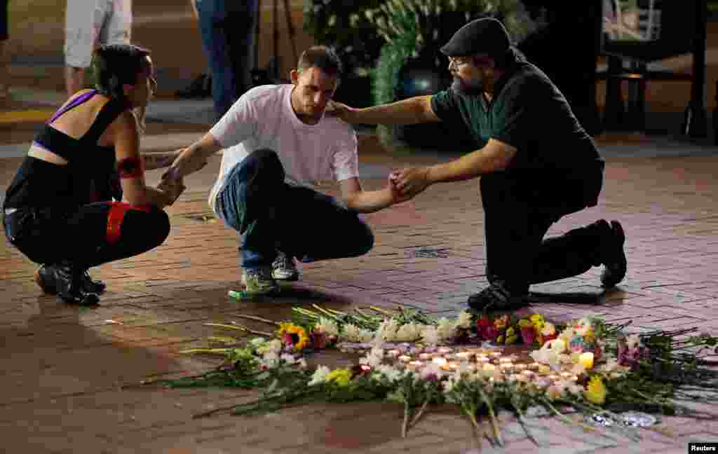 Two people stop to comfort Joseph Culver (C) of Charlottesville as he kneels at a late night vigil to pay his respect for a friend injured in a car attack on counter protesters after the &quot;Unite the Right&quot; rally organized by white nationalists in Charlottesville, Aug. 12, 2017.