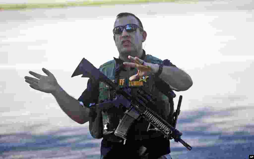 A law enforcement officer tells anxious family members to move back, Feb. 14, 2018, in Parkland, Florida. Police warned that the shooter was still at large even as ambulances converged on the scene and emergency workers appeared to be treating those possibly wounded.