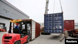 FILE - Men work on unloading the rubber imported from Belt and Road Initiative (BRI) countries at a bonded logistics center in Nantong, Jiangsu province, China, May 17, 2019.