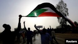 Sudanese demonstrators wave their national flag as they arrive for a protest rally demanding Sudanese President Omar Al-Bashir to step down outside the Defense Ministry in Khartoum, Sudan, April 11, 2019.