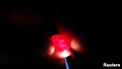 A ruby cutter inspects a ruby at his work place in Mogkok